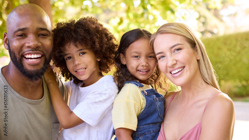Portrait Of Multi-Racial Family Standing In Garden Smiling At Camera