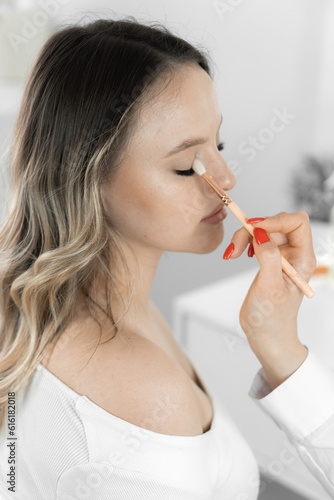 The attentive hands of the makeup artist apply makeup to the eyes of a young woman, creating an elegant pattern using special brushes and shadows different shades, giving look mystery in beauty salon