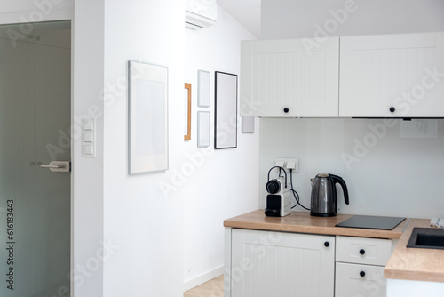 Interior design of modern trendy white kitchen and studio living room in minimalistic scandinavian style. Rent of modern flat or sale of a new apartment, modern home renovation. 
