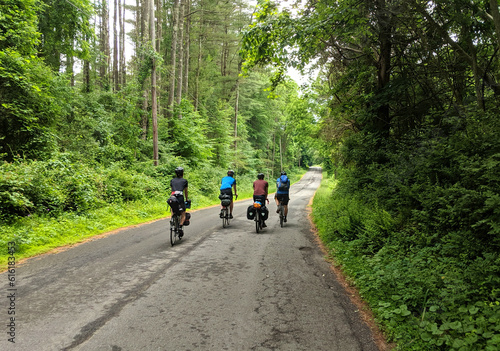 four touring cyclists riding on empty quiet country road (gravel ride, adventure cycling)