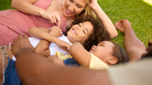 Overhead Shot Of Multi-Racial Family Lying On Grass Tickling Children