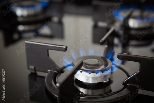 Gas supply chain, global gas crisis and price rise concept. Gas cooker with burning flames of natural gas. Close up blue fire from domestic kitchen stove top.