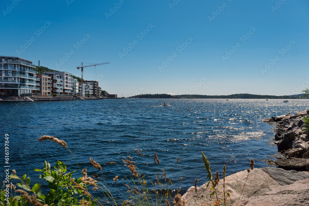 Norwegen im Sommer: Idyllische Szenerie in der Nähe des Yachthafens von Kristiansand im südlichen Norwegen mit blauem Himmel, Natur und einigen Häusern strahlendem Sonnenschein, Copy Space