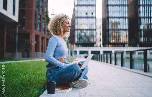 Photography Cheerful ethnic woman surfing laptop in street