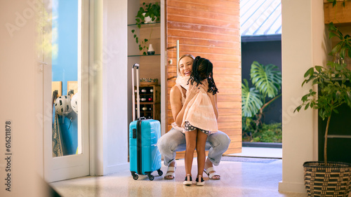 Daughter Greeting Mother Returning Home With Luggage From Trip Away 