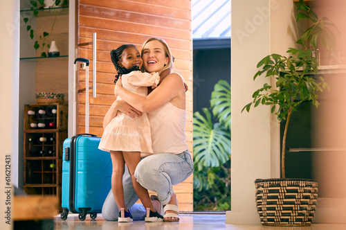 Daughter Greeting Mother Returning Home With Luggage From Trip Away 