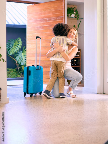 Son Greeting Mother Returning Home With Luggage From Trip Away 