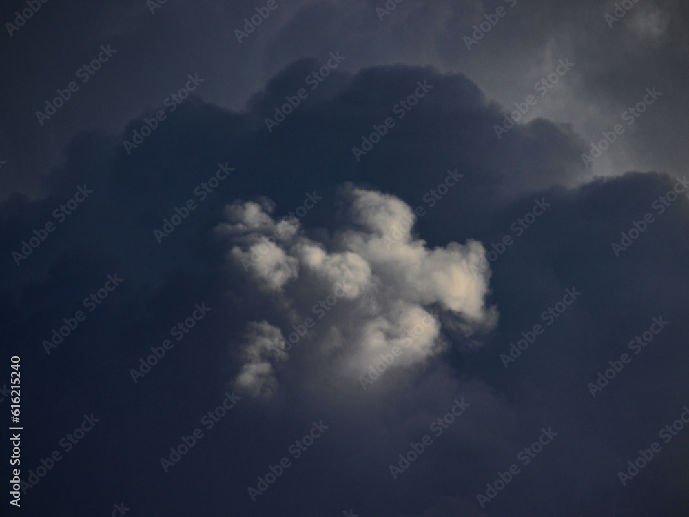 The top of a dark gray shaded cloud lit by sunbeam.