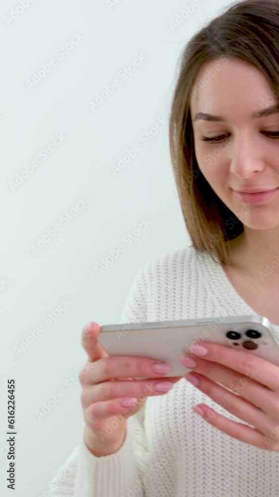 young girl holding a phone in her hands horizontally gentle manicure Light clothes white background advertising smile The very charm of a beautiful woman young girl holding a phone in her hands horizontally gentle manicure Light clothes white background advertising smile The very charm of a beautiful woman
