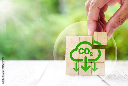 CO2 emission reduction concept. Green industries business concept. Net zero emissions. Renewable energy, sustainable technology, ecology solutions. Hand puts wooden cubes CO2 emission reduction icon.