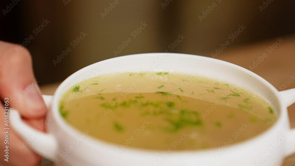 Macro view: The chicken bouillon with noodles, dill and chicken meat . Soup in a white bowl. 4k slow motion Macro view: The chicken bouillon with noodles, dill and chicken meat . Soup in a white bowl. 4k slow motion