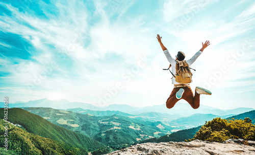 Happy man with backpack jumping on top of the mountain - Delightful hiker with arms up standing over the cliff - Sport and travel life style concept © Davide Angelini