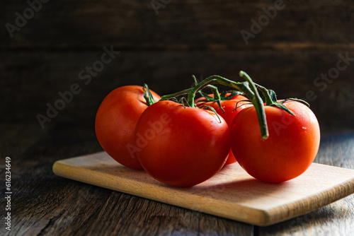 A branch of ripe tomatoes on a cutting board in the kitchen.