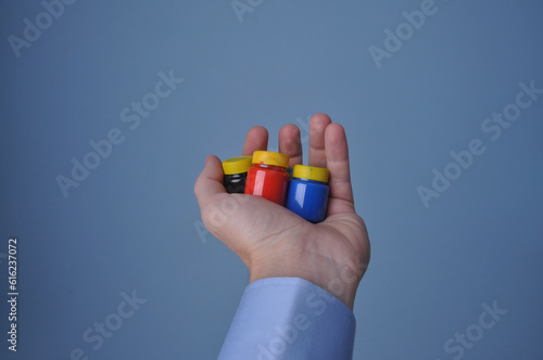 mão segurando tintas coloridos 
