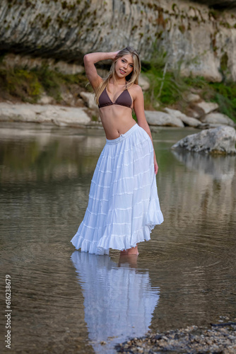 Fototapeta Naklejka Na Ścianę i Meble -  A Lovely Blonde Bikini Model Enjoys The Summer Weather On A Lake