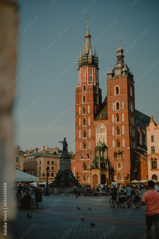 Fototapeta premium View of Saint Mary Basilica in Krakow, Poland on a summer sunny day viewed from the arcades at main city square. Basilica in Krakow, Poland on a summer sunny day viewed from the arcades at square.
