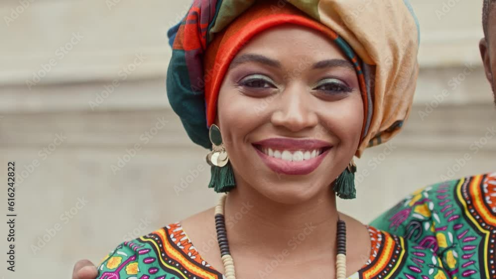 Close up portrait of smiling african woman. Female dressed up in headscarf posing at camera. Woman with makeup wearing traditional african earrings and necklace. Female in colorful turban and outfit. Close up portrait of smiling african woman. Female dressed up in headscarf posing at camera. Woman with makeup wearing traditional african earrings and necklace. Female in colorful turban and outfit.