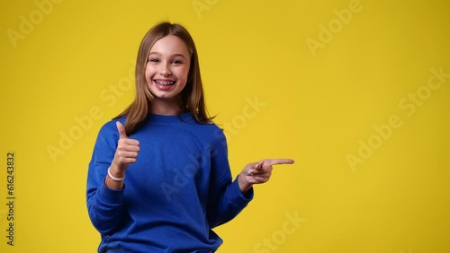 4k slow motion video of one girl who points to the right side and showing thumb up over yellow background.