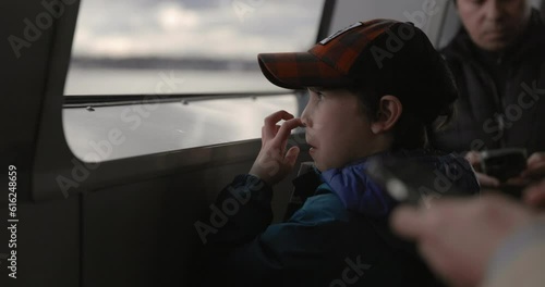 Young boy picking nose while on public transportation ferry photo