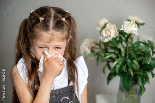 girl blowing nose near the flowers