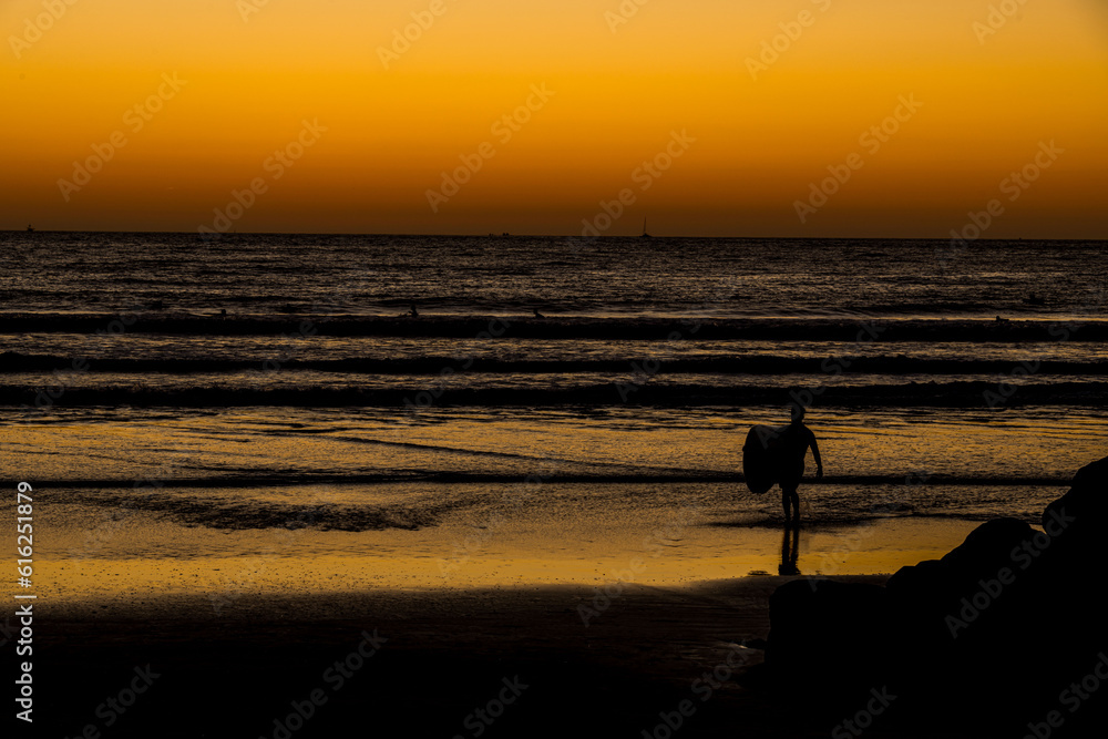 Surfer Heading into the Surf at Sunset