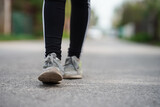 Women's feet in sneakers walk on asphalt