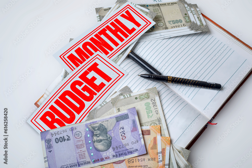 Monthly budget planning: Indian currency notes with pen on a open notebook on a white background, top view. Monthly budget planning: Indian currency notes with pen on a open notebook on a white background, top view.