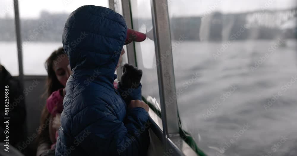 Boy traveling on ferry with mother and sister looks out window - side profile Boy traveling on ferry with mother and sister looks out window - side profile