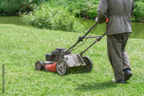 A man mows grass on the lawn with a four-wheel lawn mower. Gardener mowing the lawn. Landscape design.