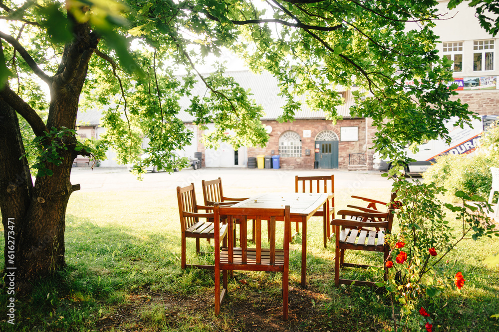 Sitzecke mit Tisch und Stühlen draußen im Garten unter einem Baum. Schutz vor Sonne