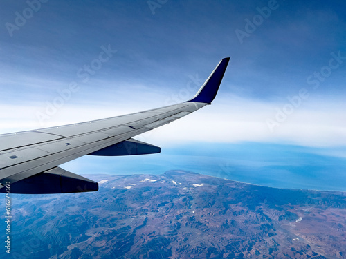 Wing of an airplane flying over the Sea of Cortez and the Pacific Ocean  in the Mexican state of Baja California  in a landscape that combines the beautiful blue of the sky and the sea. Aircraft.