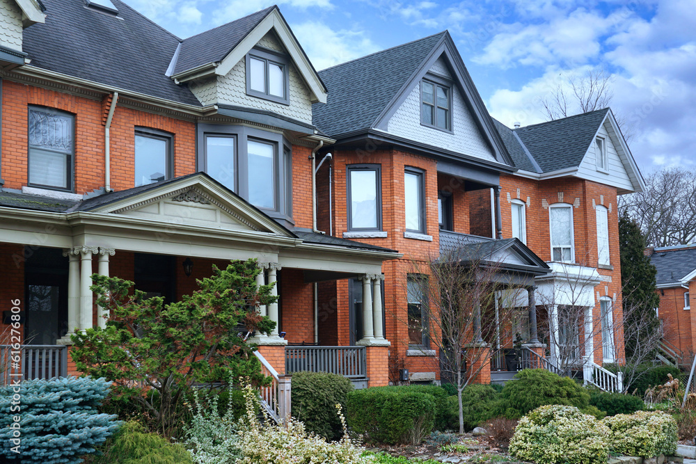 Residential street with row of brick semi-detached houses with gables and large front porch Residential street with row of brick semi-detached houses with gables and large front porch