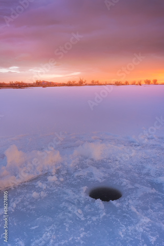 Ice fishing on a frozen lake at Sunrise