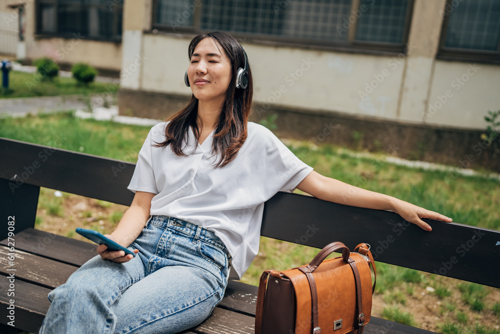  Japanese woman singing while listening music with headphones and mobile phone outside on the street