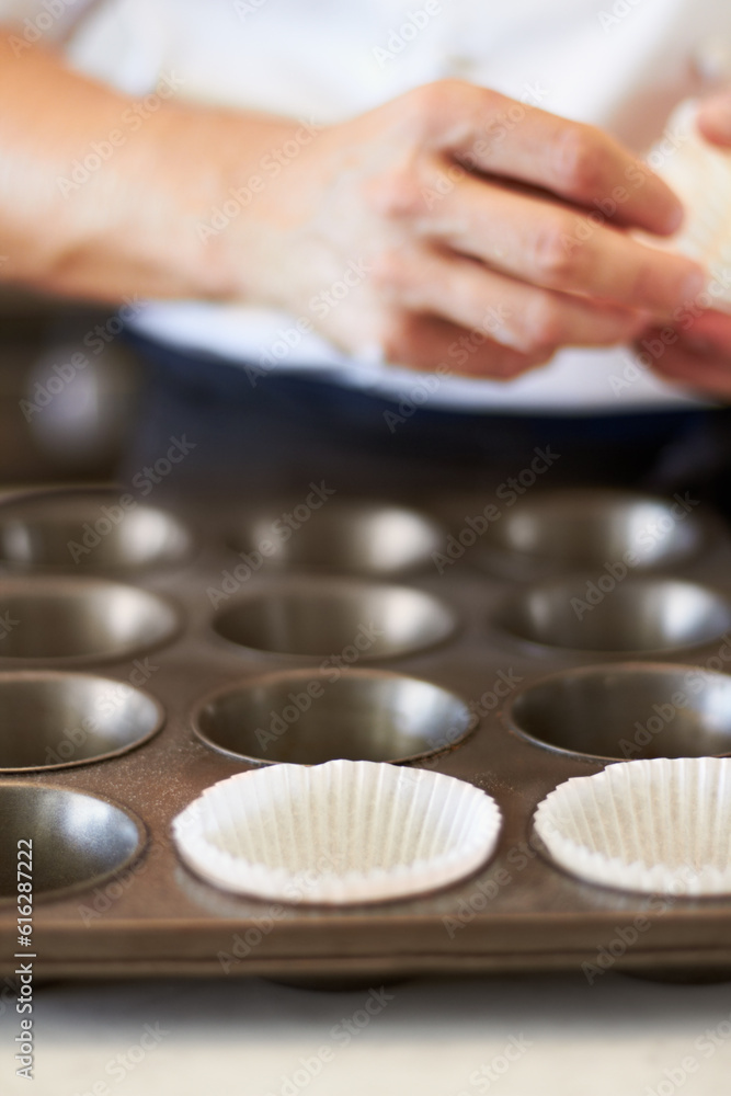 Cupcake tray, person hands and baking in kitchen with muffin wrapper and cooking closeup in bakery. Prepare, paper cup and food with chef in restaurant, coffee shop or cafe with sweet cake or pastry