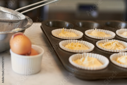 Cupcake tray, batter and baking in a kitchen with muffin mix or wrapper and cooking in a bakery. Closeup, paper cup and food with chef in a restaurant, coffee shop or cafe with sweet cake and pastry