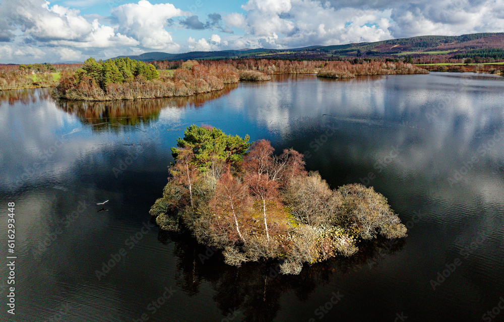 Loch Kinord crannog prehistoric Iron Age artificial manmade island settlement. Muir of Dinnet, Grampian, Scotland. Spring. Aerial view looking east