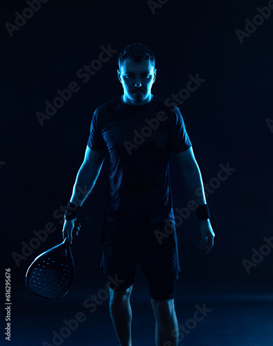 Padel tennis player. Man athlete with paddle tenis racket on black background. Sport concept. Download a high quality photo for sports website.