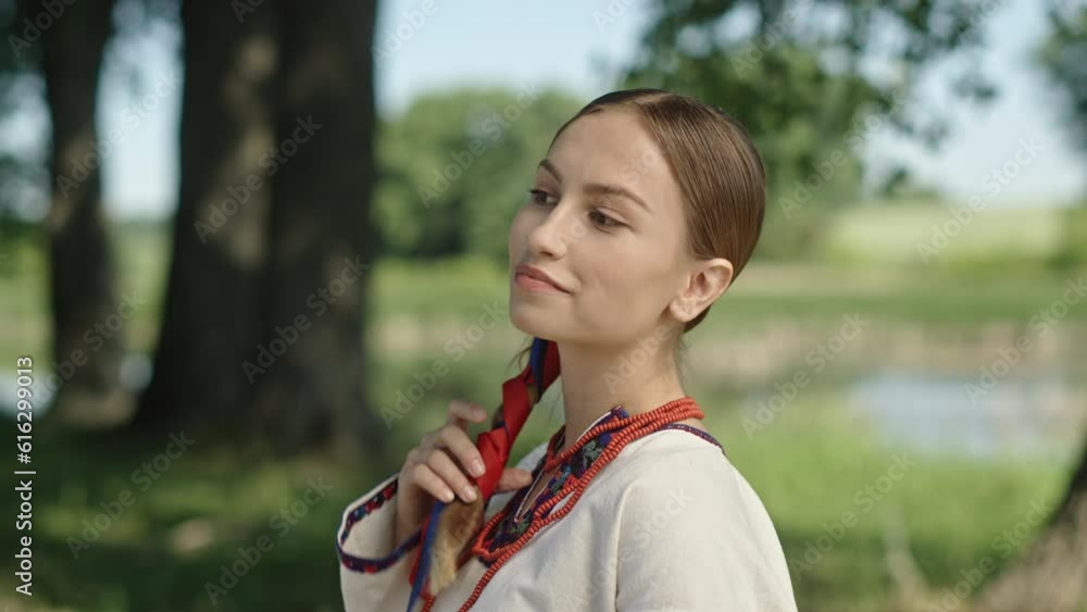 Portrait of a beautiful Ukrainian girl with a long braid in an embroidered national costume against the background of a picturesque landscape of a green meadow. Portrait of a beautiful Ukrainian girl with a long braid in an embroidered national costume against the background of a picturesque landscape of a green meadow.