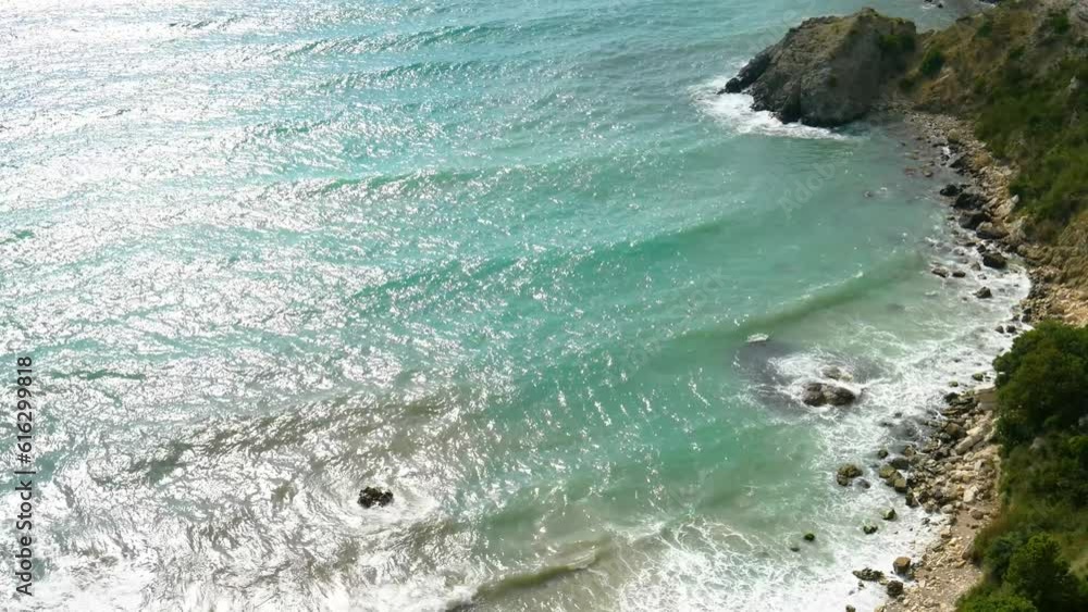 Top view of blue sea water with white waves and stones. Seascape. Clean clear sea water. Abstraction. Minimalism. There are no people in the photo. There is free space to insert. Top view of blue sea water with white waves and stones. Seascape. Clean clear sea water. Abstraction. Minimalism. There are no people in the photo. There is free space to insert.