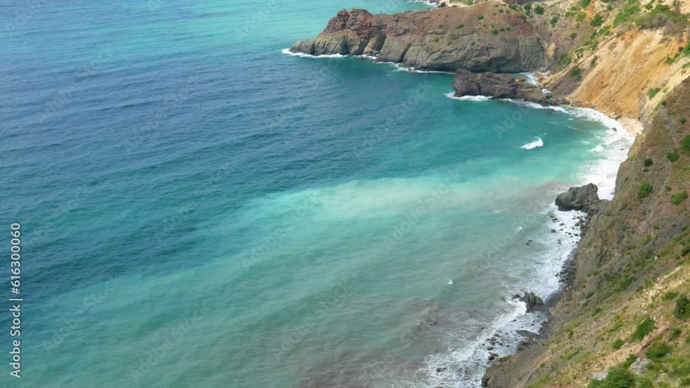 The waves of the sea crash against the rocky shore. The shore with stones and small waves. The movement of the sea. The waves of the sea crash against the rocky shore. The shore with stones and small waves. The movement of the sea.