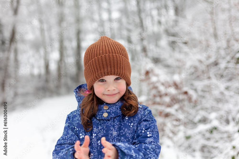 Adorable little girl having fun in beautiful winter forest. Cute child playing outdoors. Winter activities for kids.
