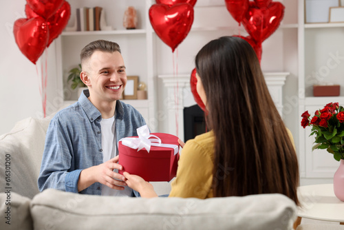 Man receiving gift box from his girlfriend at home. Valentine's day celebration