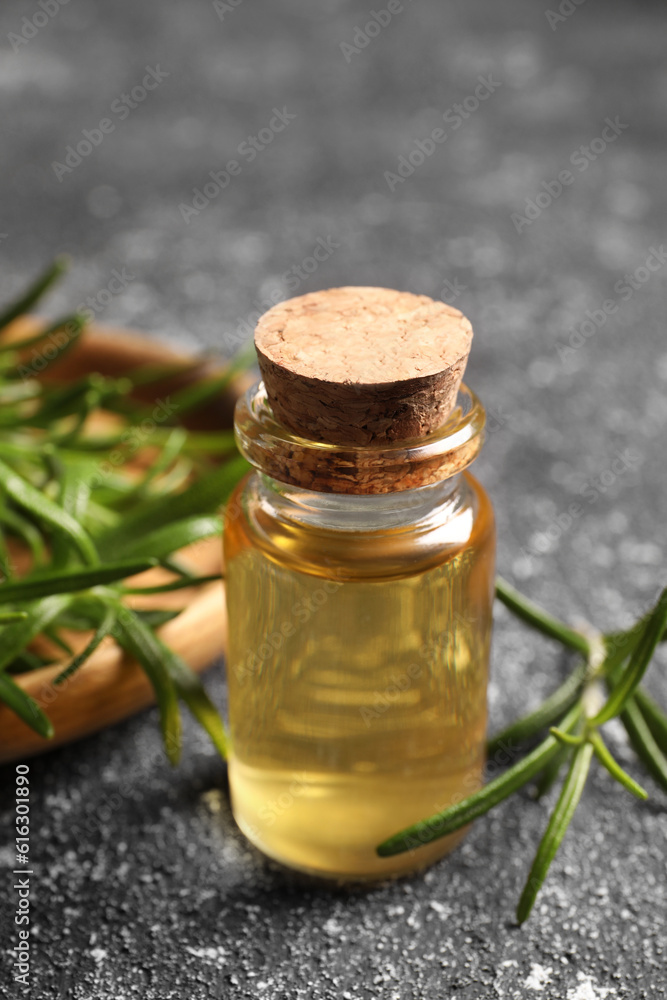 Bottle with oil and fresh rosemary on grey textured table, closeup Bottle with oil and fresh rosemary on grey textured table, closeup