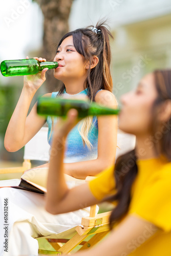 Photography Group of Happy young Asian man and woman friends enjoy and fun reunion meeting party at home backyard with playing guitar, singing, eating food and drinking beer together on summer holiday vacation
