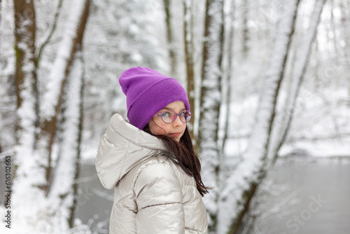 Portrait of a beautiful girl in a pink hat and glasses in the winter forest