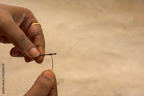 Close up shot of an woman trying to put tread in the eye of the needle.