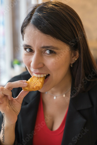 taking a bite of a nugget  having lunch a woman with long straight hair  lifestyle and natural beauty  enjoying while tasting food