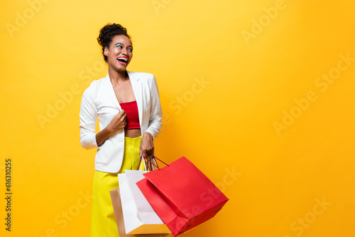 Fashionable African American woman carrying shopping bags in isolated yellow color background studio shot, Summer sale concept