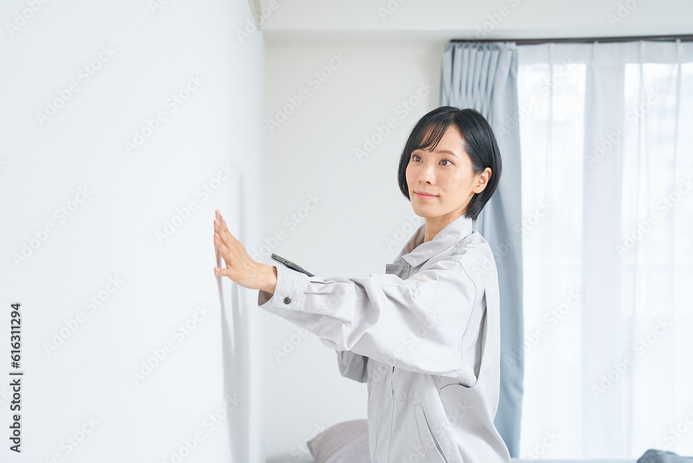 住宅の壁の状態を調べる作業着姿の女性 住宅の壁の状態を調べる作業着姿の女性